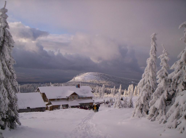 Schronisko "Na Śnieżniku", za nim Średniak (1210 m npm), a w tle zachmurzone niebo nad Kotliną Kłodzką.